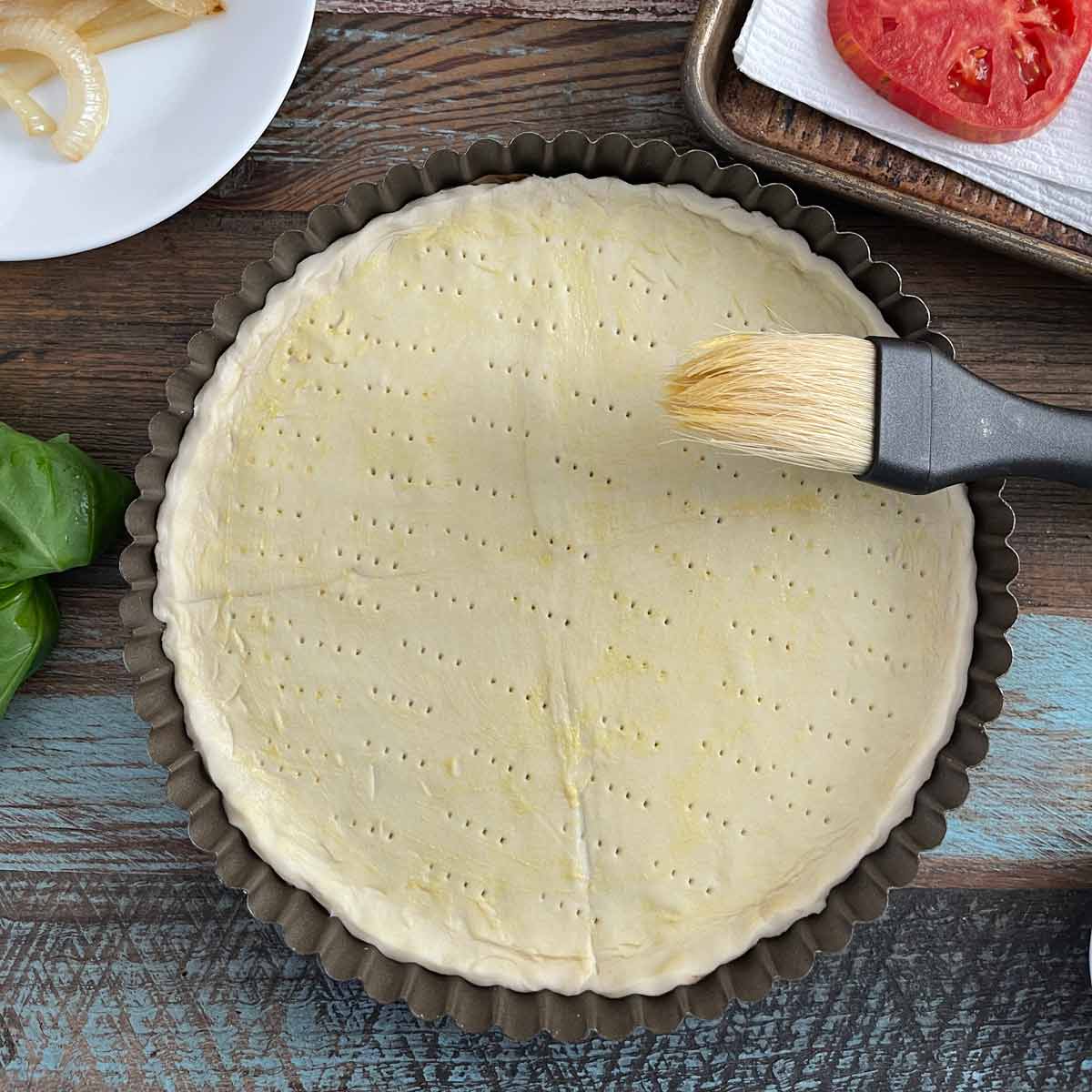 Puff pastry being brushed with Dijon mustard.