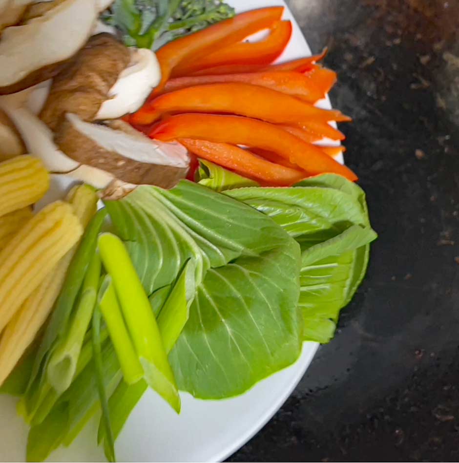 Image shows vegetable being added to the wok.