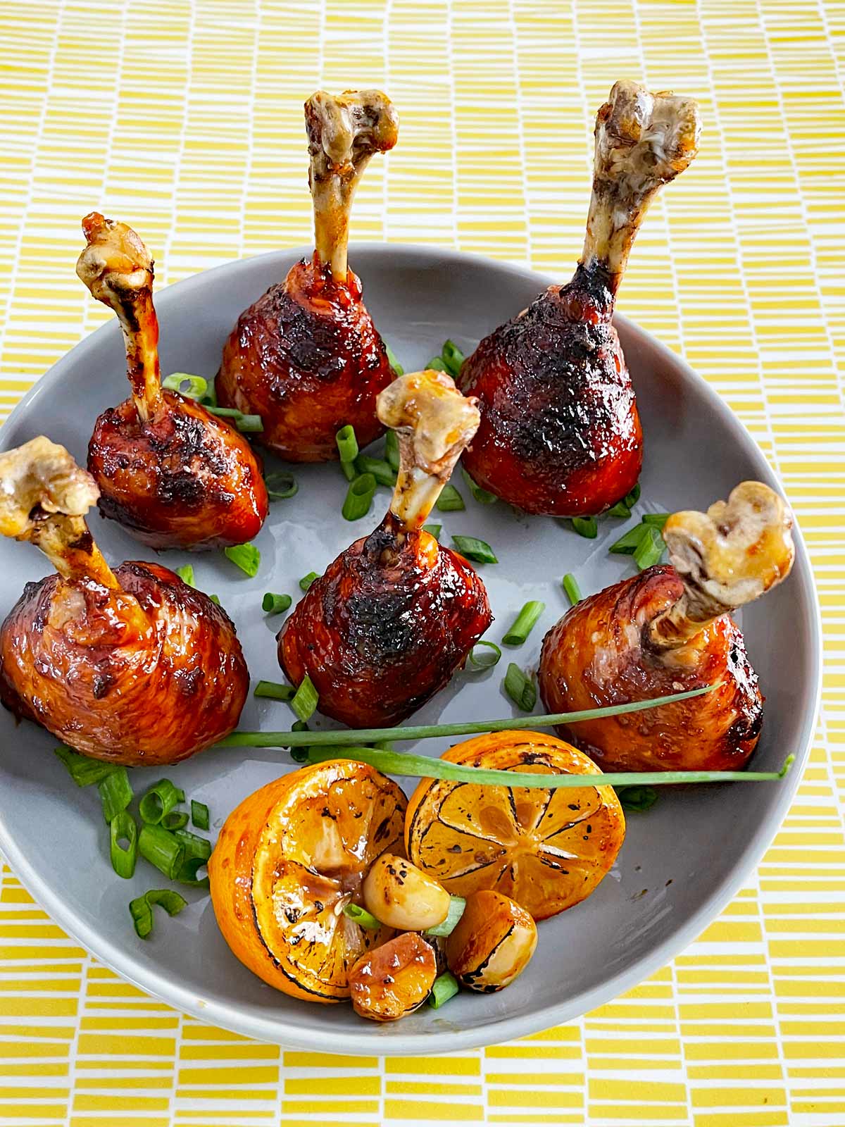 Six chicken drumsticks with glaze and prepared to expose the bone.