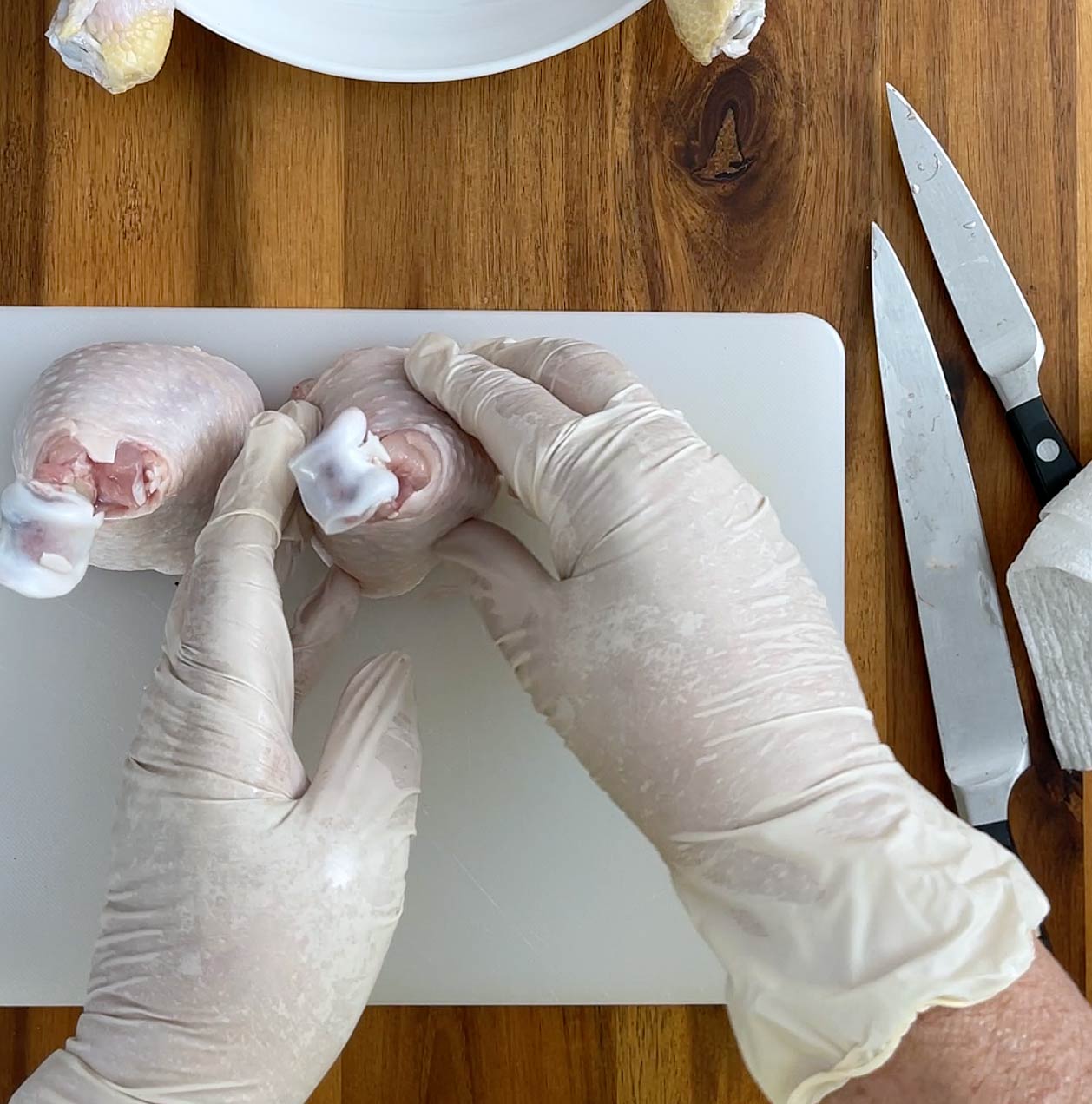 Hands sitting prepped chicken leg upright.