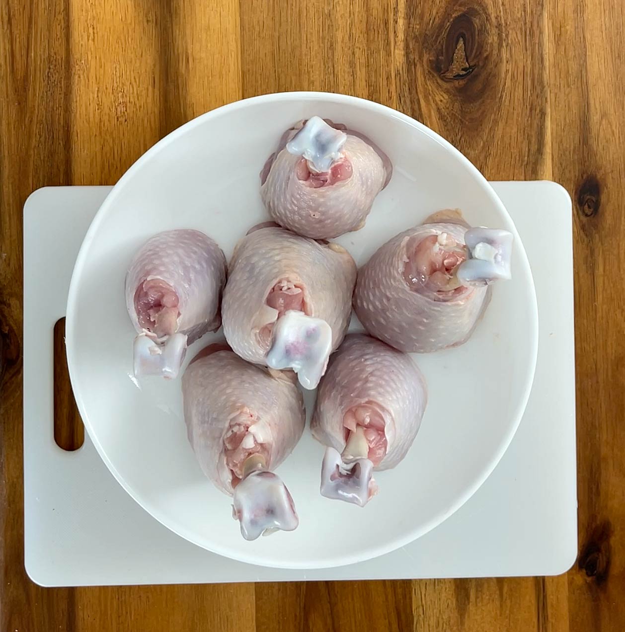 Six chicken legs upright in a bowl.