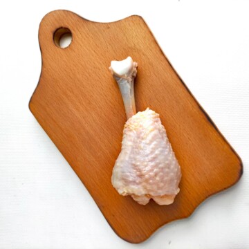 Chicken drumstick on cutting board. 
