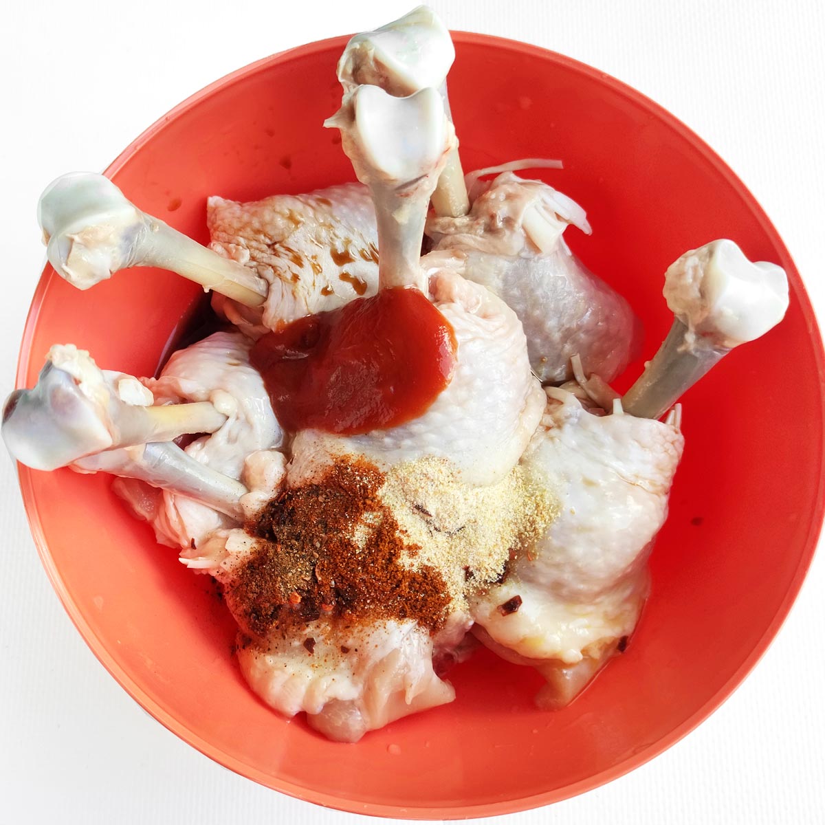 Chicken wings and spice and oil in a big bowl.