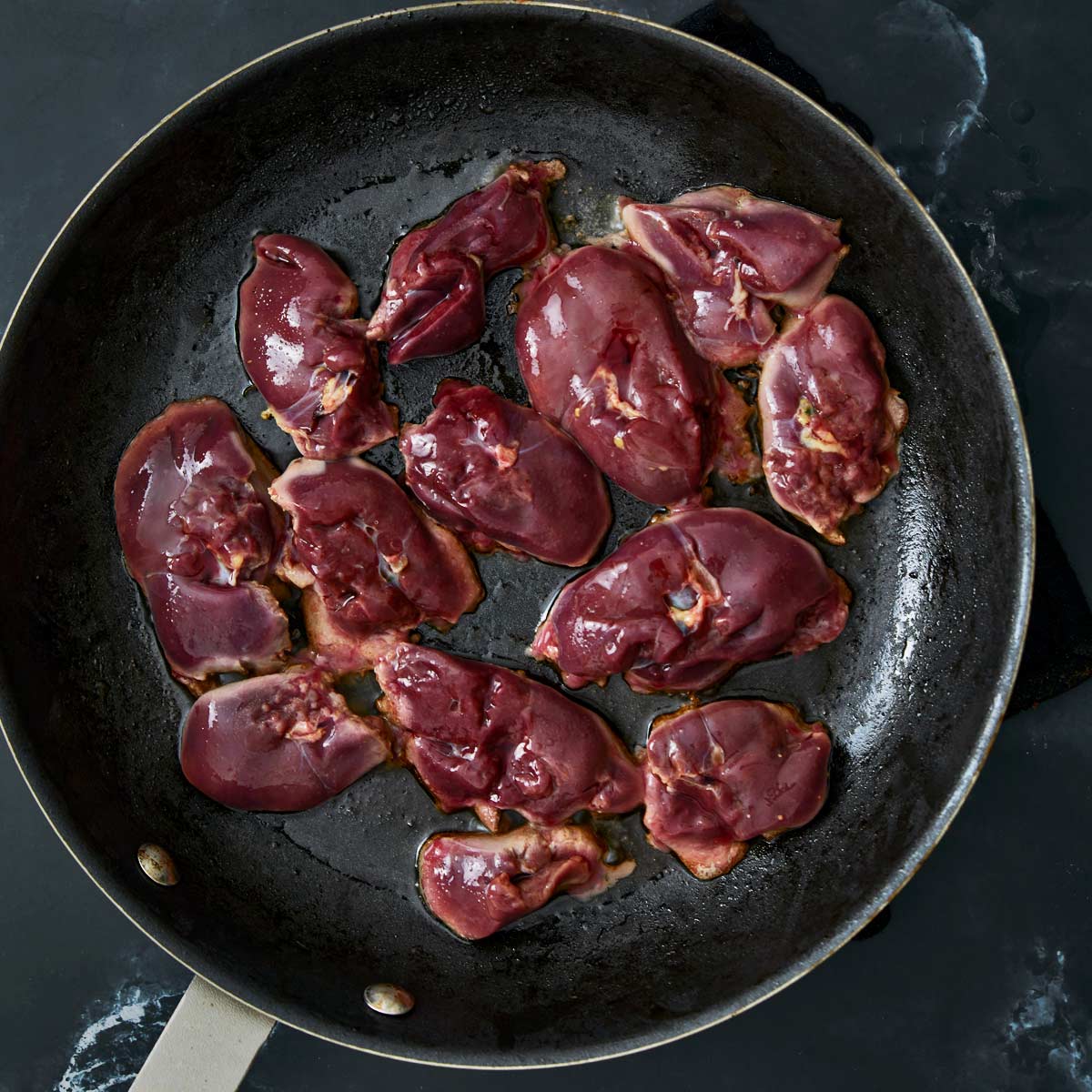 Skillet with chicken livers cooking on one side.