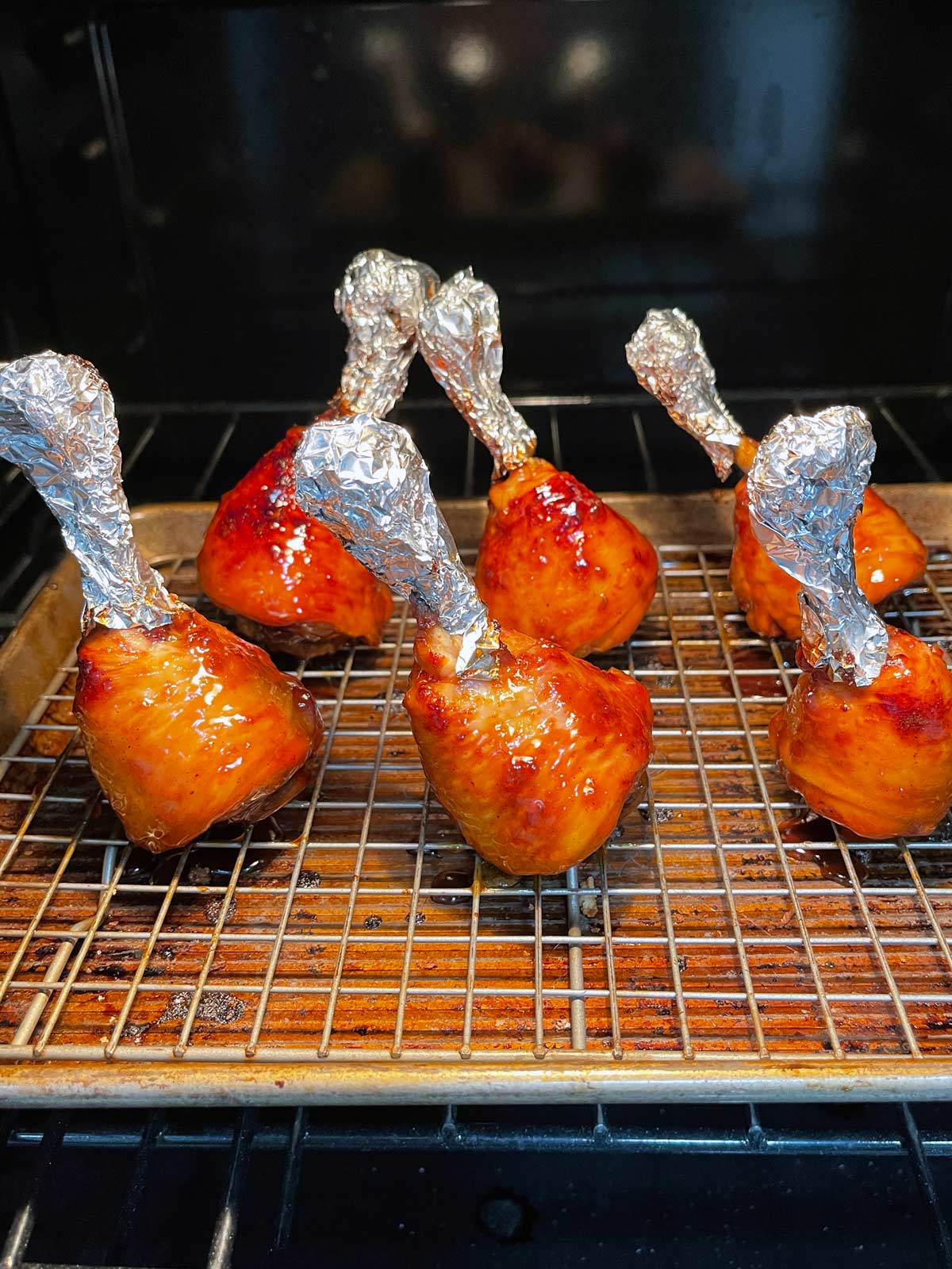 Chicken lollipops on baking tray with foil over exposed bone/