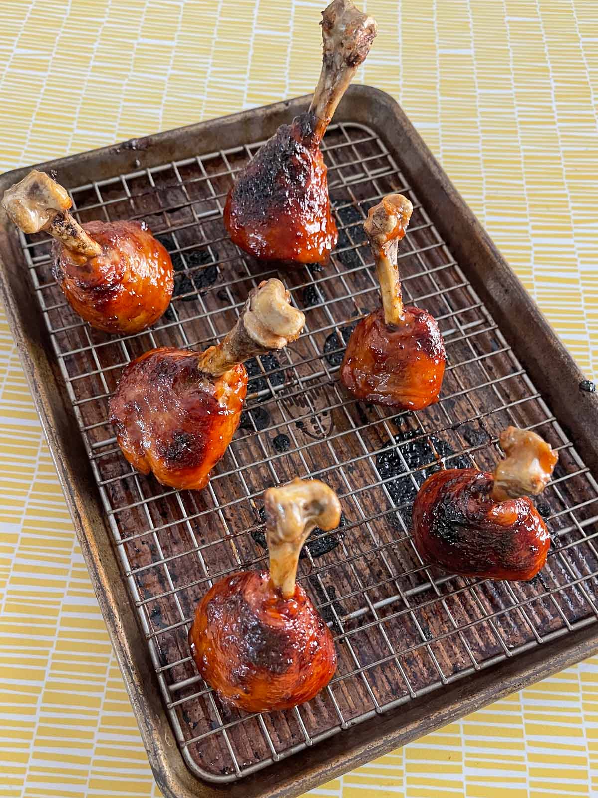 Fully cooked chicken lollipops are golden brown on a baking sheet.