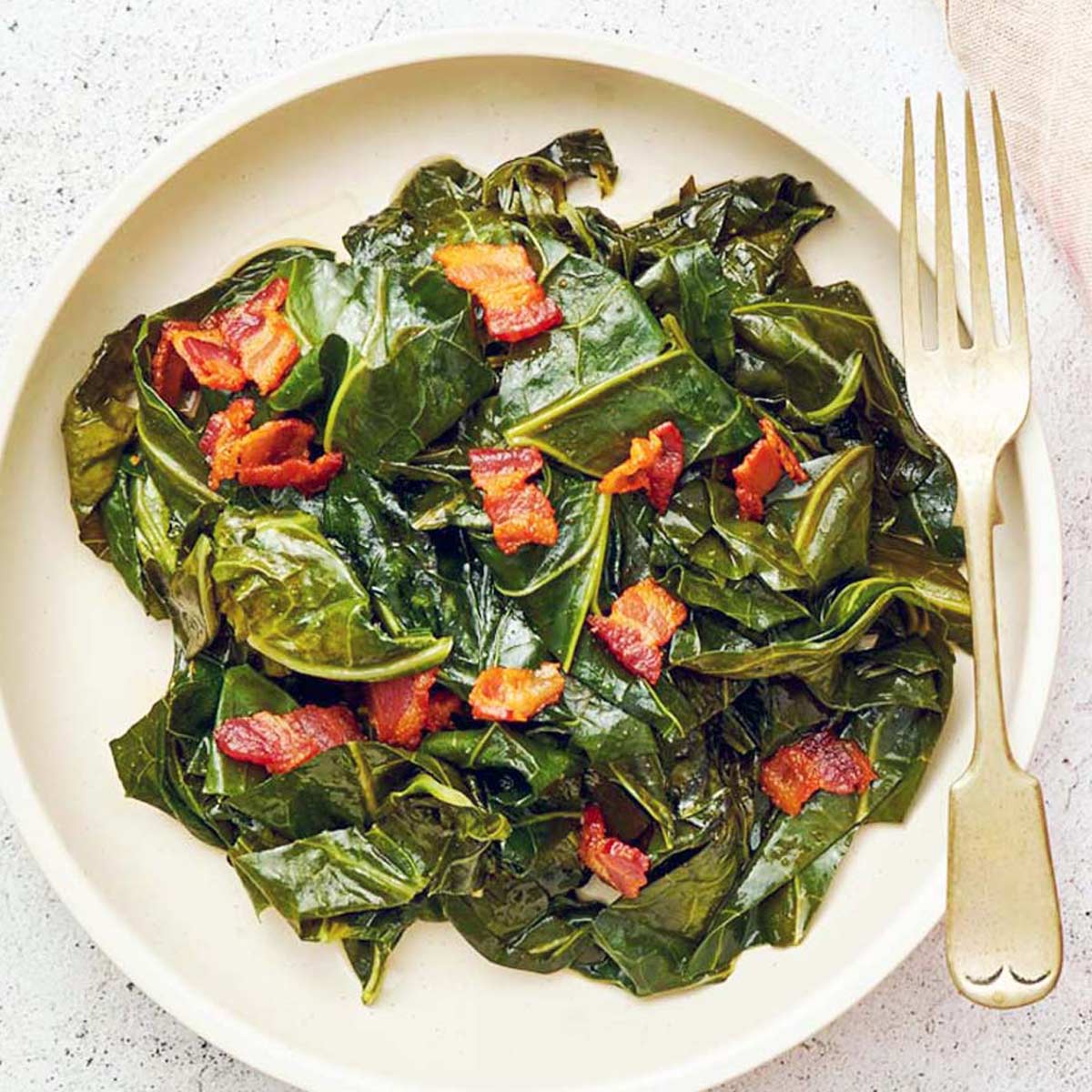 A plate of cooked collard greens and bacon.
