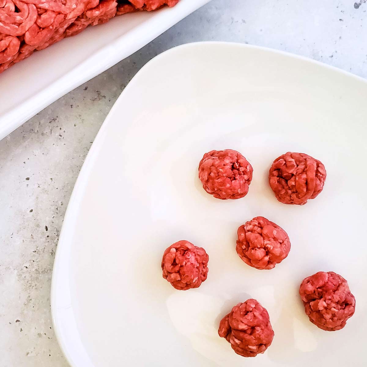 Small beef meatball on a white plate.