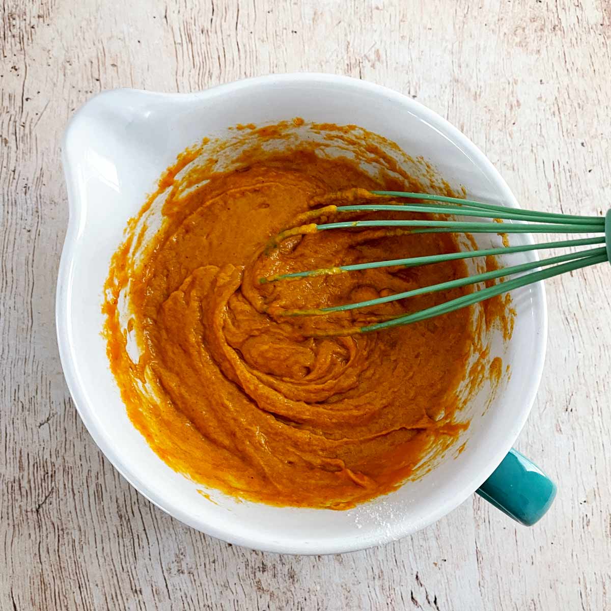 Bowl with whisk beating the wet and dry ingredients together.
