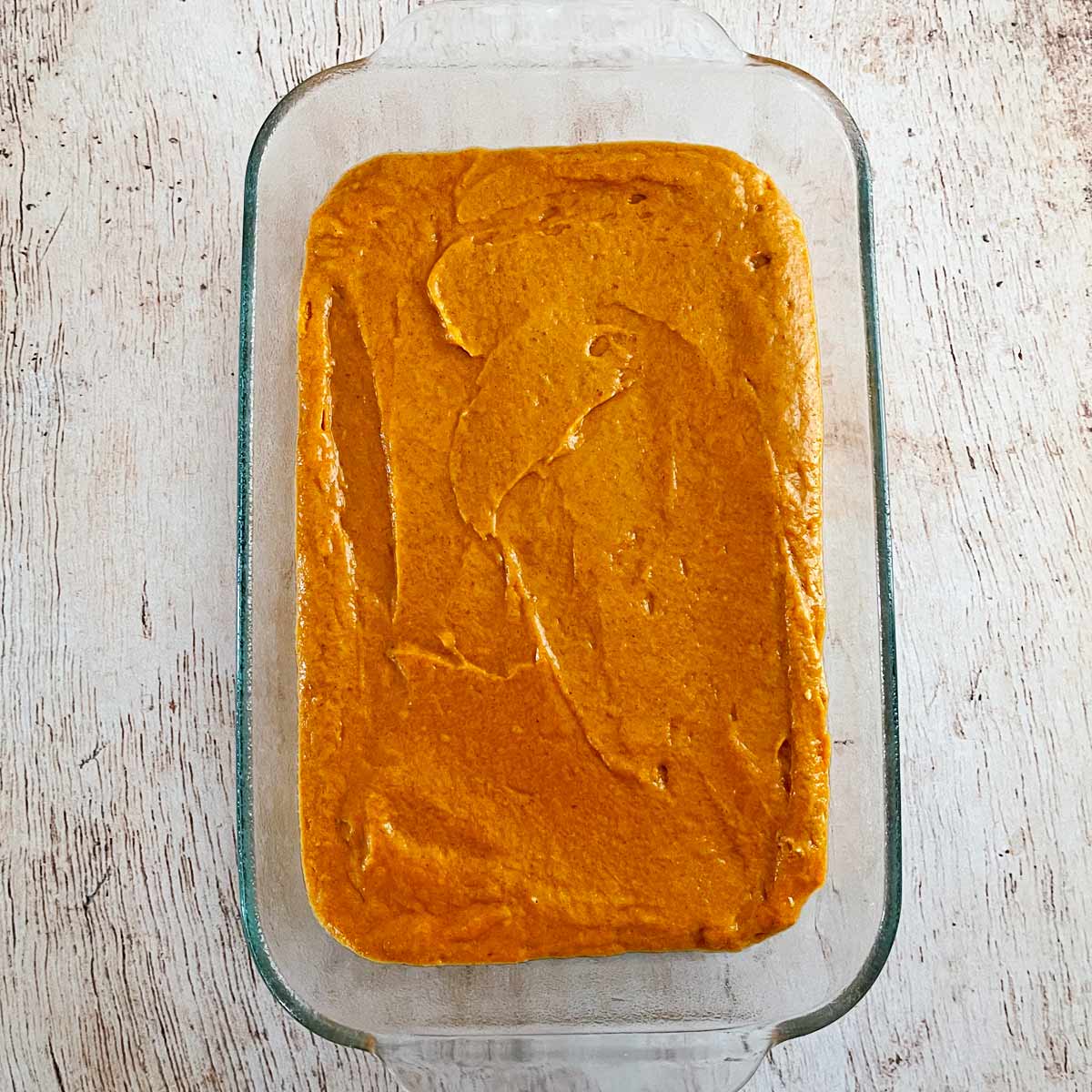 Prepared baking dish with pumpkin cake batter inside.