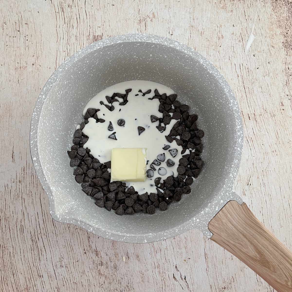 Pot with cream, butter, and chocolate chips.