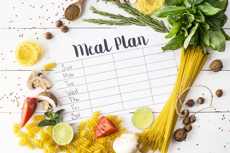 Meal planning calendar with fruits and vegetables scattered around.