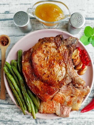 Two pork chops on a plate with green beans.