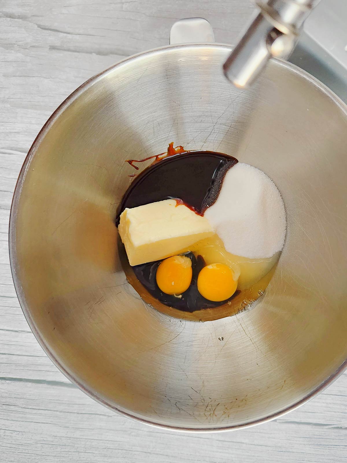 Bowl of stand mixer with butter, eggs, molasses, and sugar.