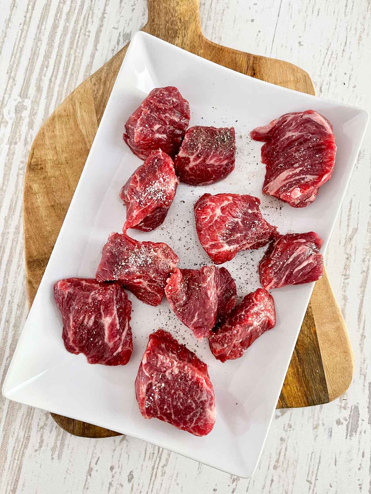Plate with cubed beef chuck seasoned with salt and pepper.