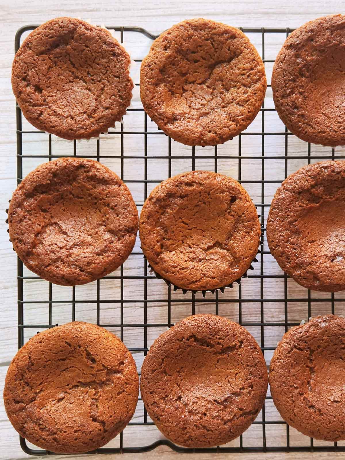 Fully baked gingerbread cupcakes cooling on a wire rack.