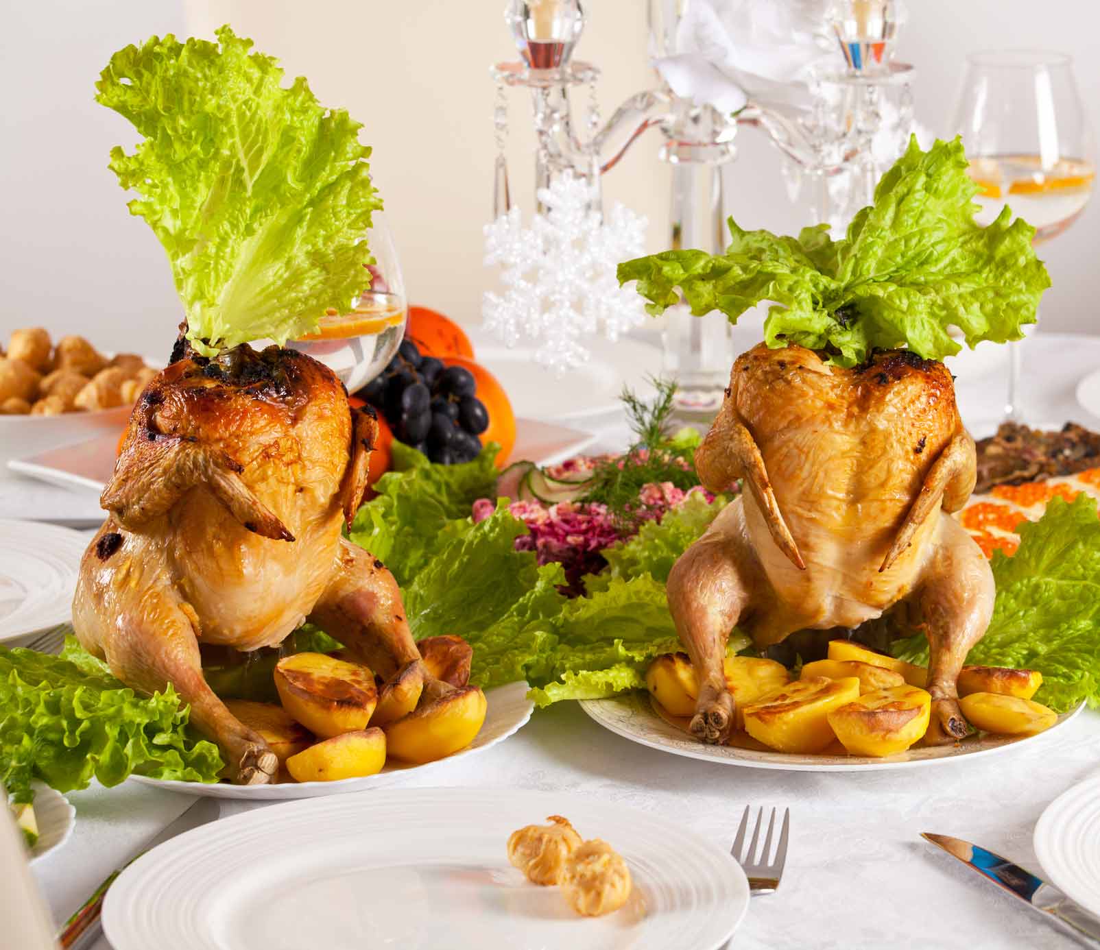 Two cornish game hens standing upright with lettuce leaf hats.