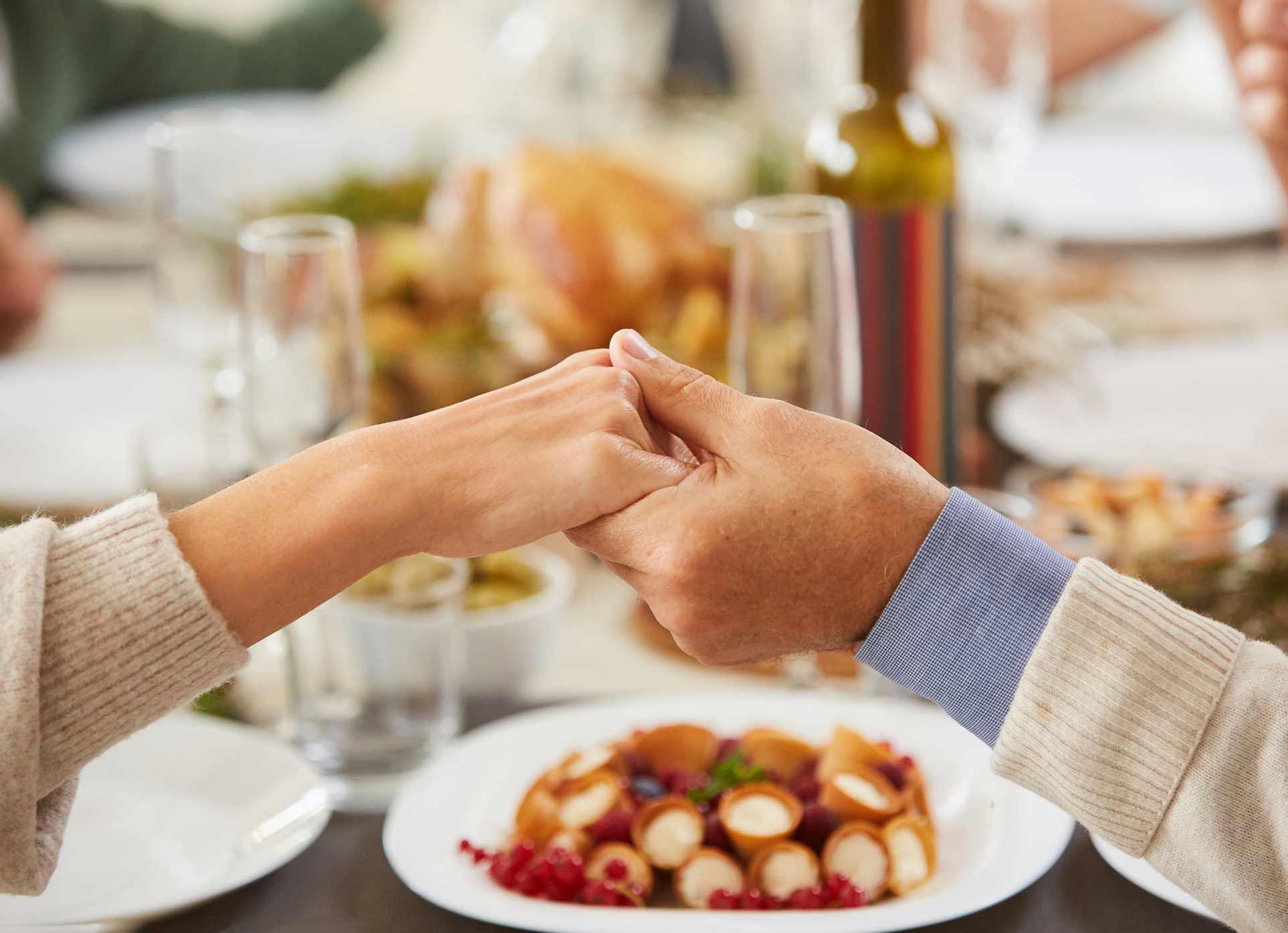 Couple holding hands across the dinner table.