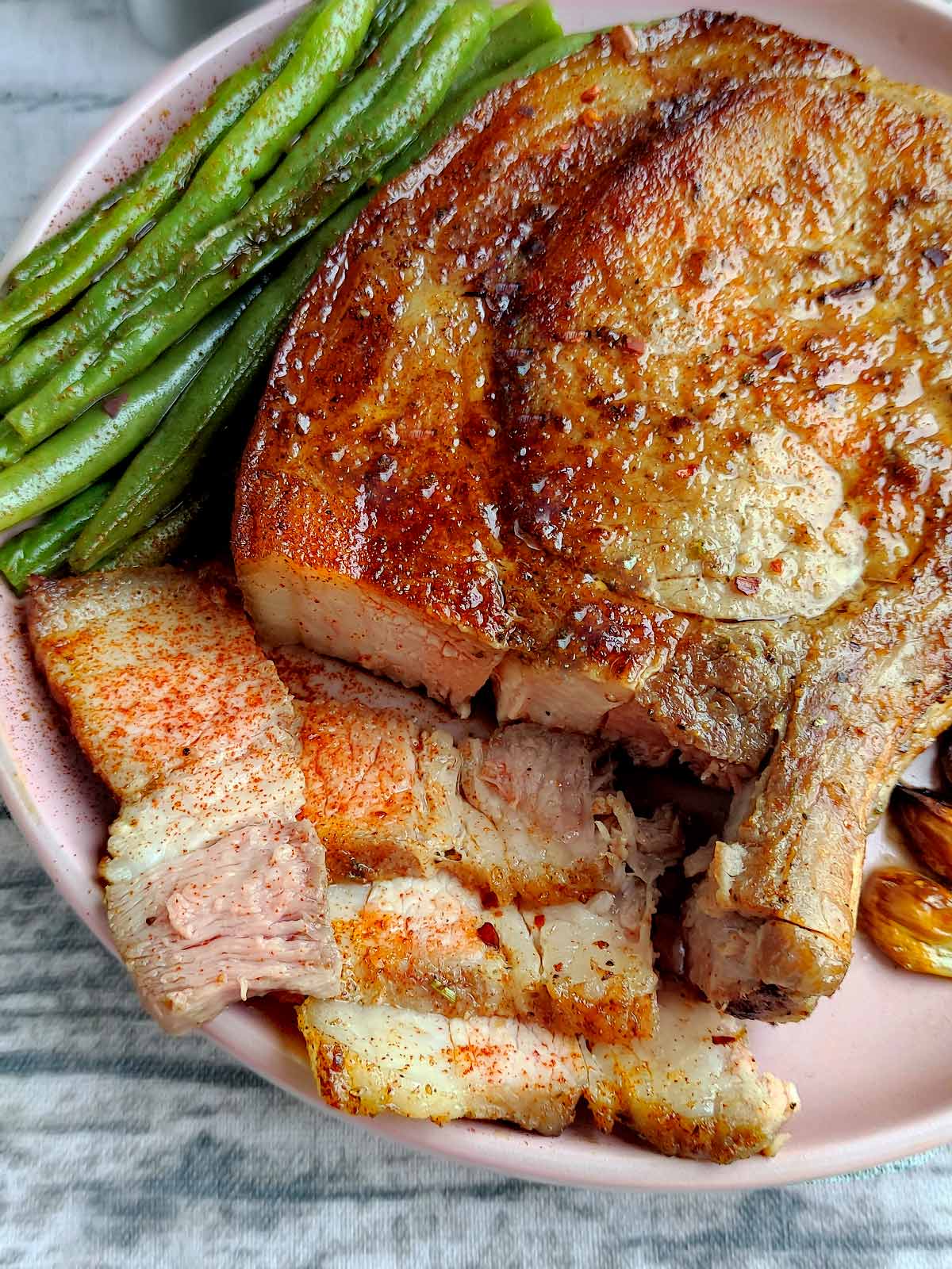 Fully cooked pork chop on plate with slices.