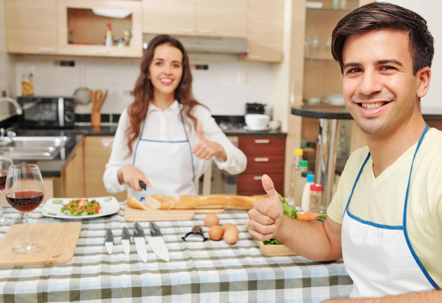 Small kitchen with a smiling young couple cooking together.