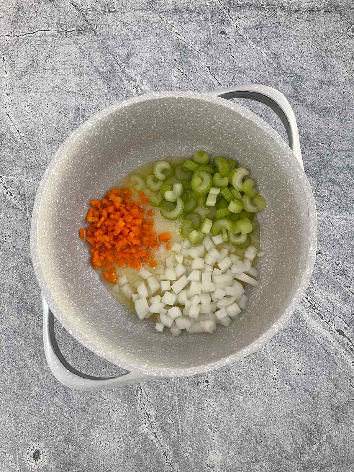 Dutch oven with onion, carrot, and celery cooking in butter.
