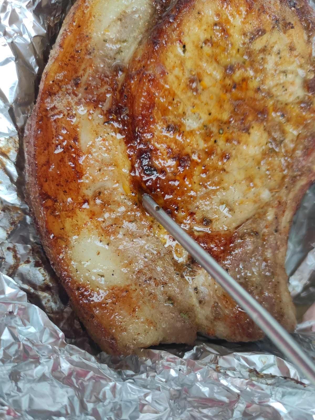 Pork chop temperature being checked with thermometer.