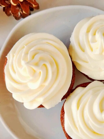 Three frosted cupcakes on a white plate.