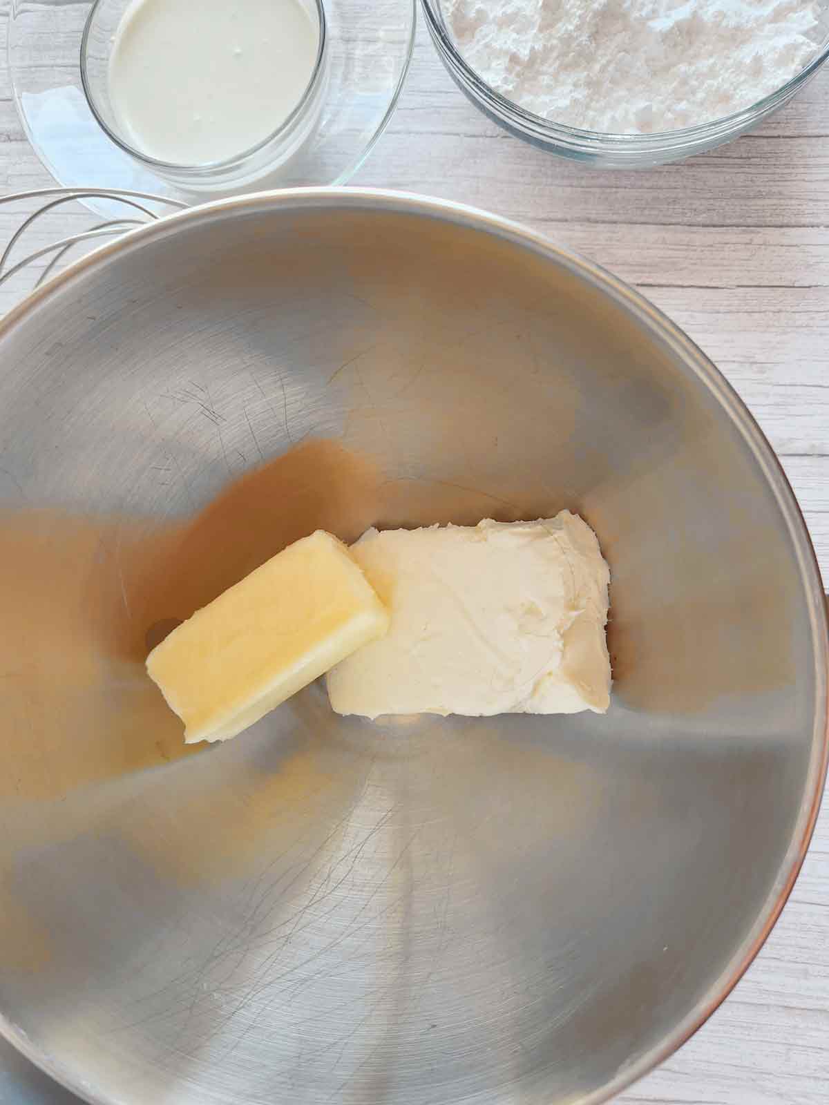 Butter and cream cheese in the bowl of a stand mixer.