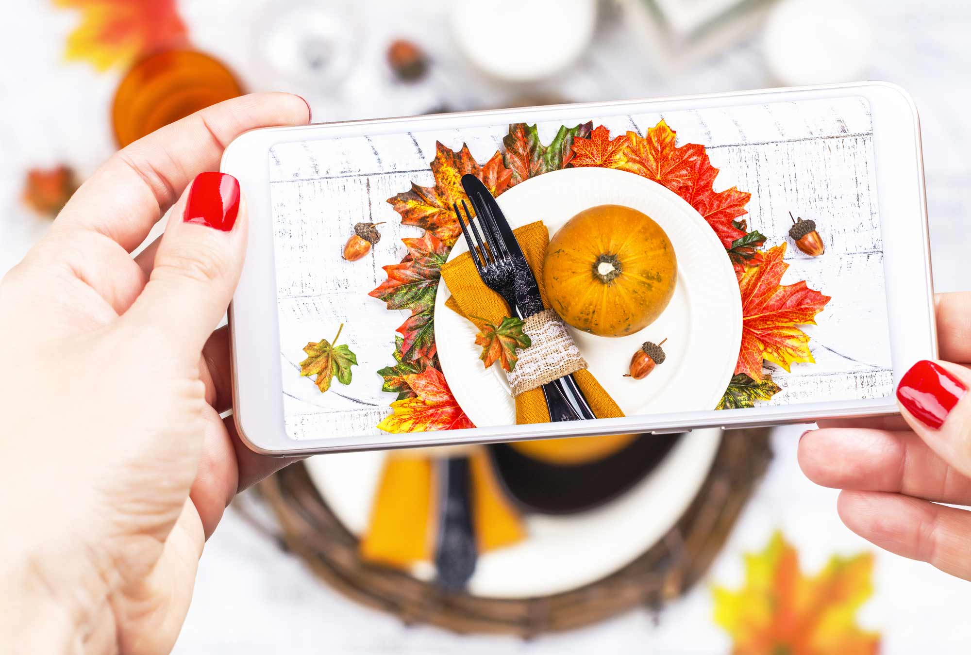 Hands taking a cell phone picture of a beautiful Thanksgiving table.