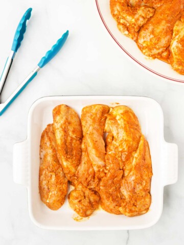 Uncooked pieces of chicken in an ovenproof baking dish.