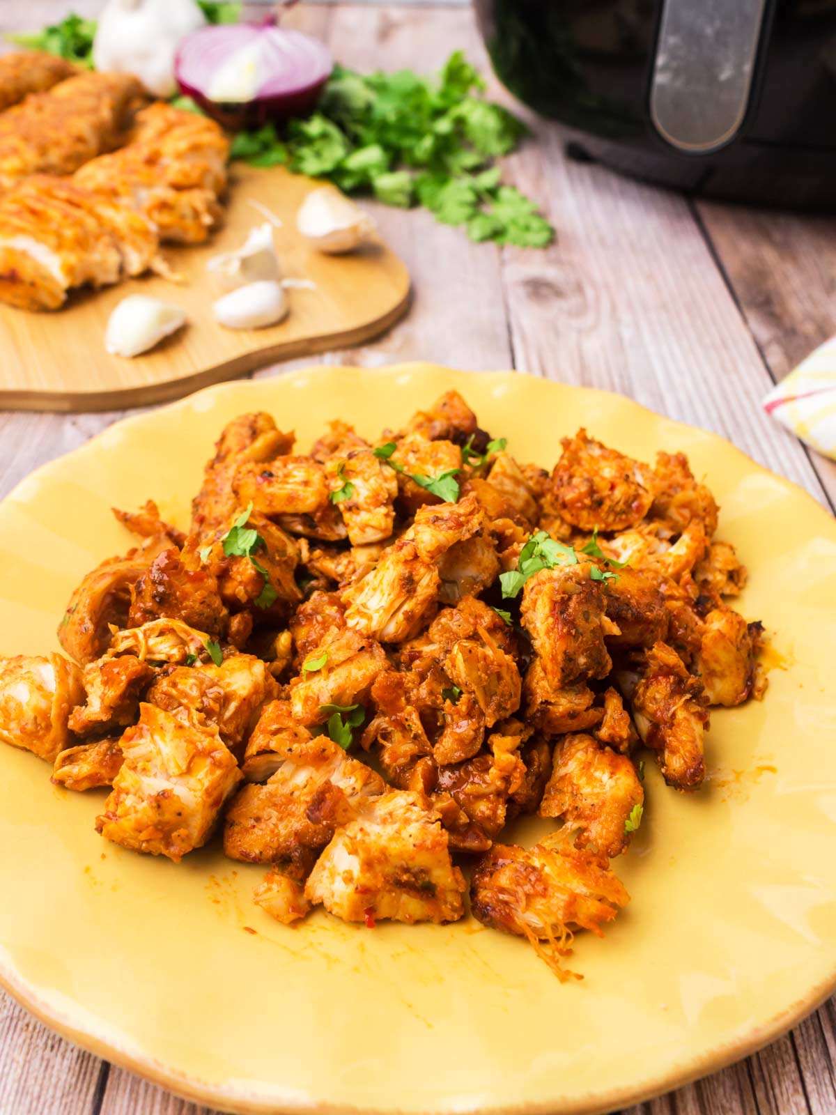 Cut and diced chicken pieces on a yellow serving plate.