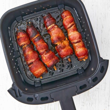 Air fryer basket with bacon wrapped chicken.