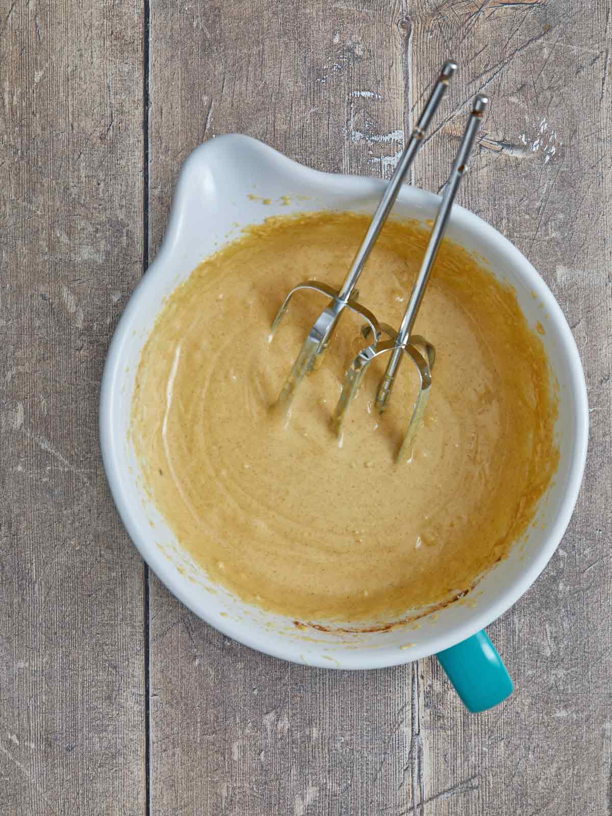 Bowl of mixed cake batter with beaters in.