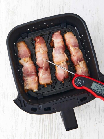 Skewers in the air fryer basket with meat thermometer reading 145 degrees.