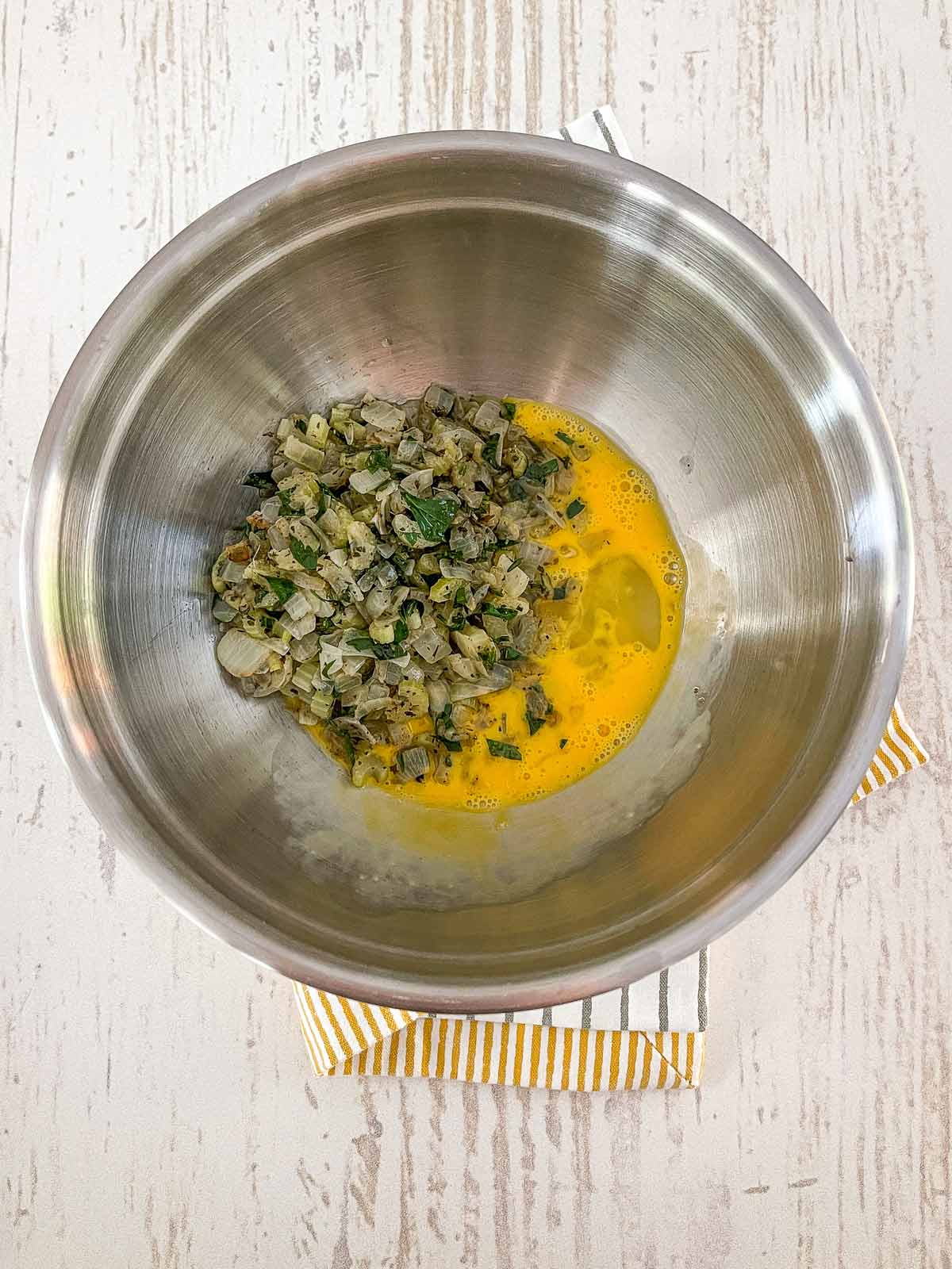Large bowl with beaten egg and veggie mixture.