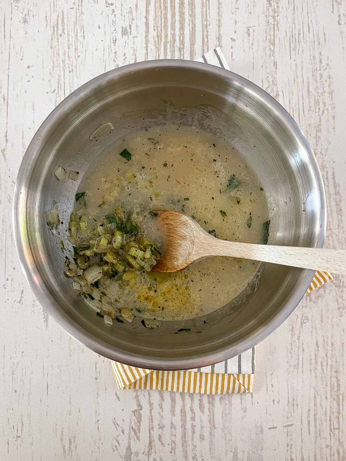 Adding the broth to the large bowl with the other ingredients.