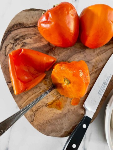 Persimmons on cutting board with top cut off.