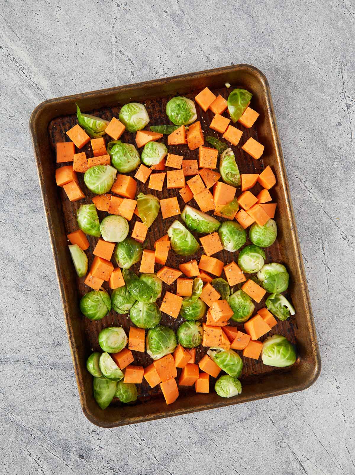 Baking sheet with vegetables with pepper sprinkled on.