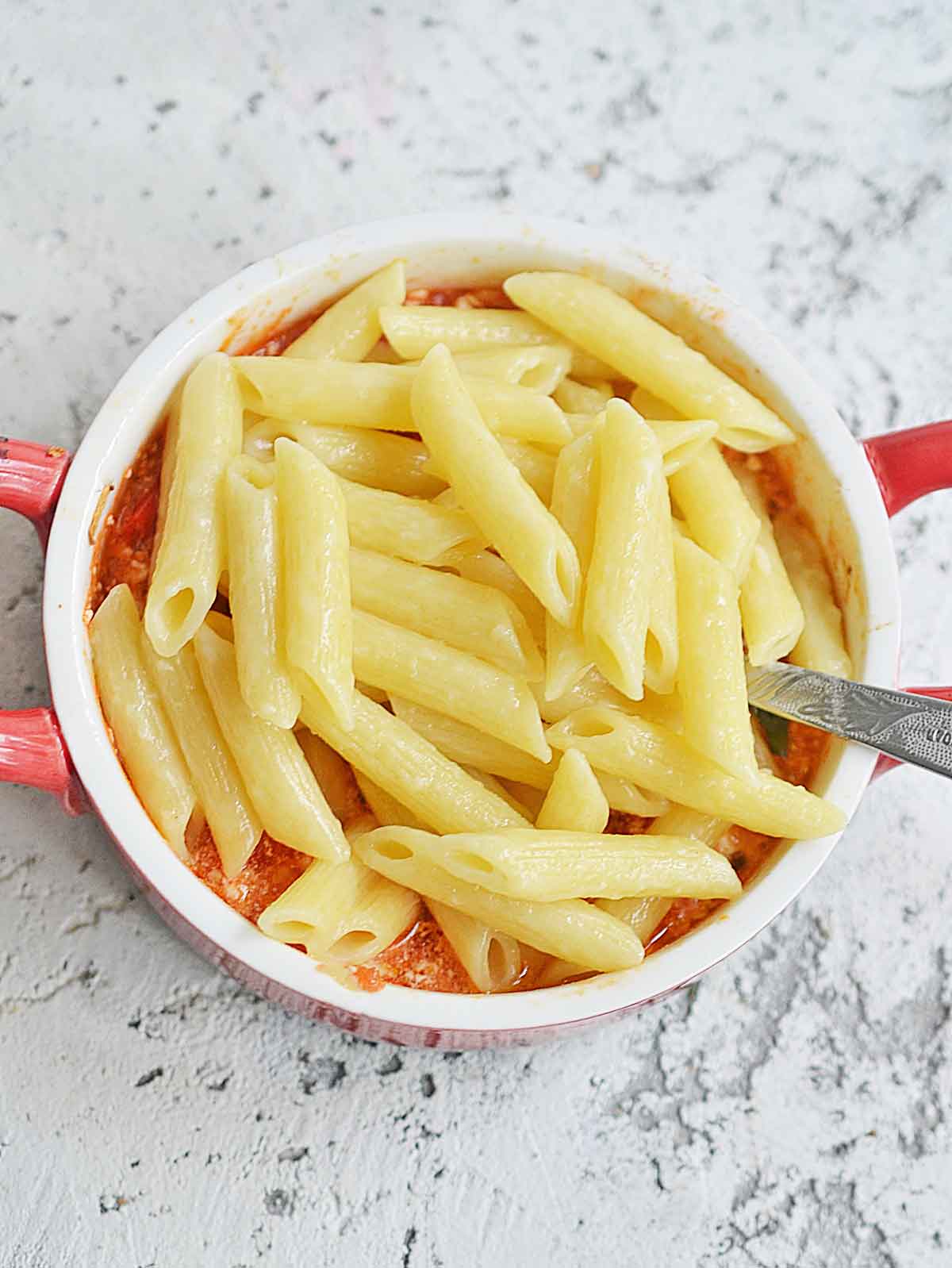 Pasta added to baking dish with the tomato feta sauce.