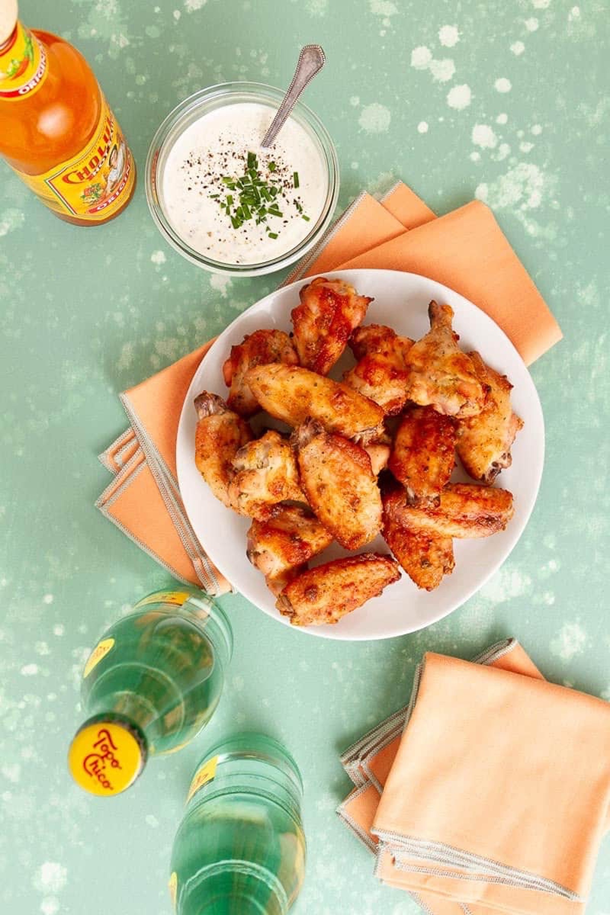 Chicken wings in a bowl with beverage and ranch dressing dip.