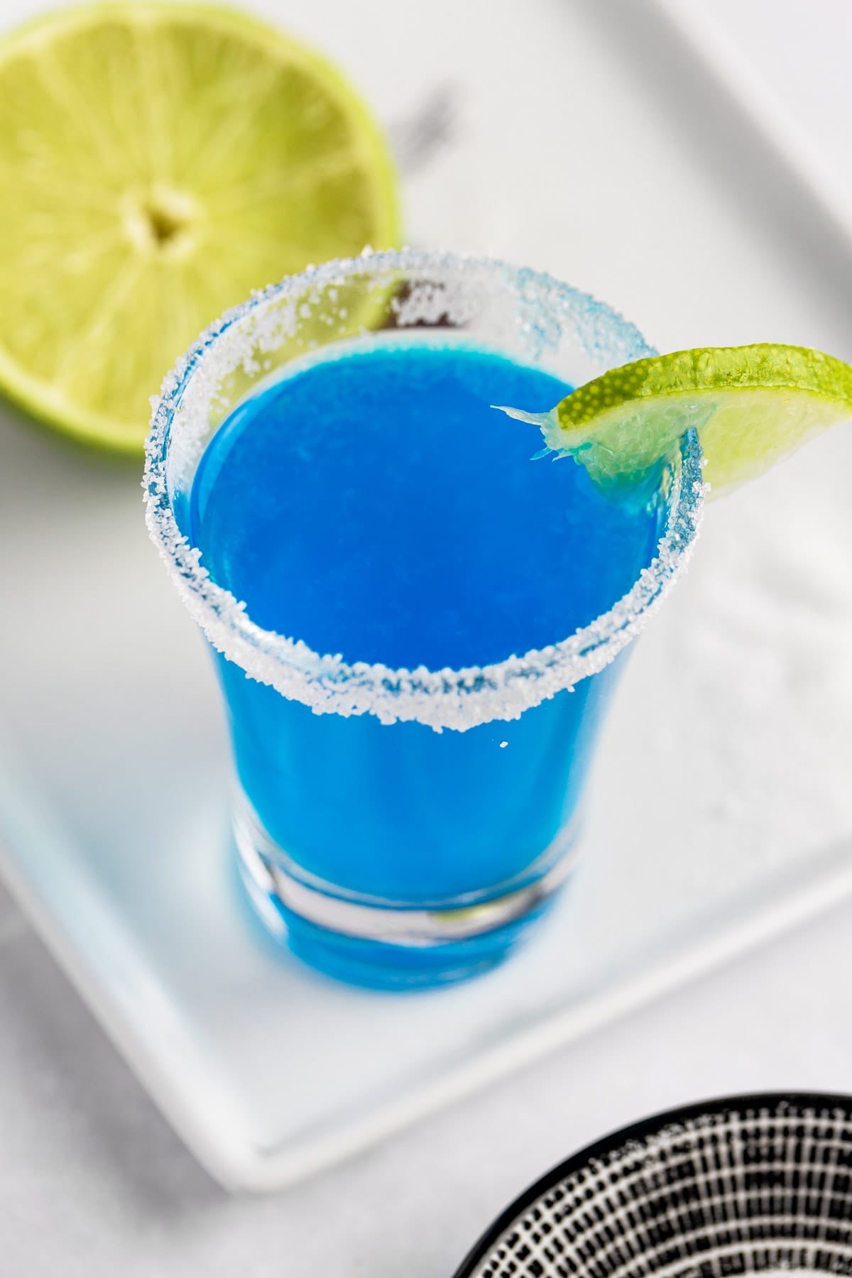 Blue Kamikaze drink with a slice of lime on the edge of the glass.