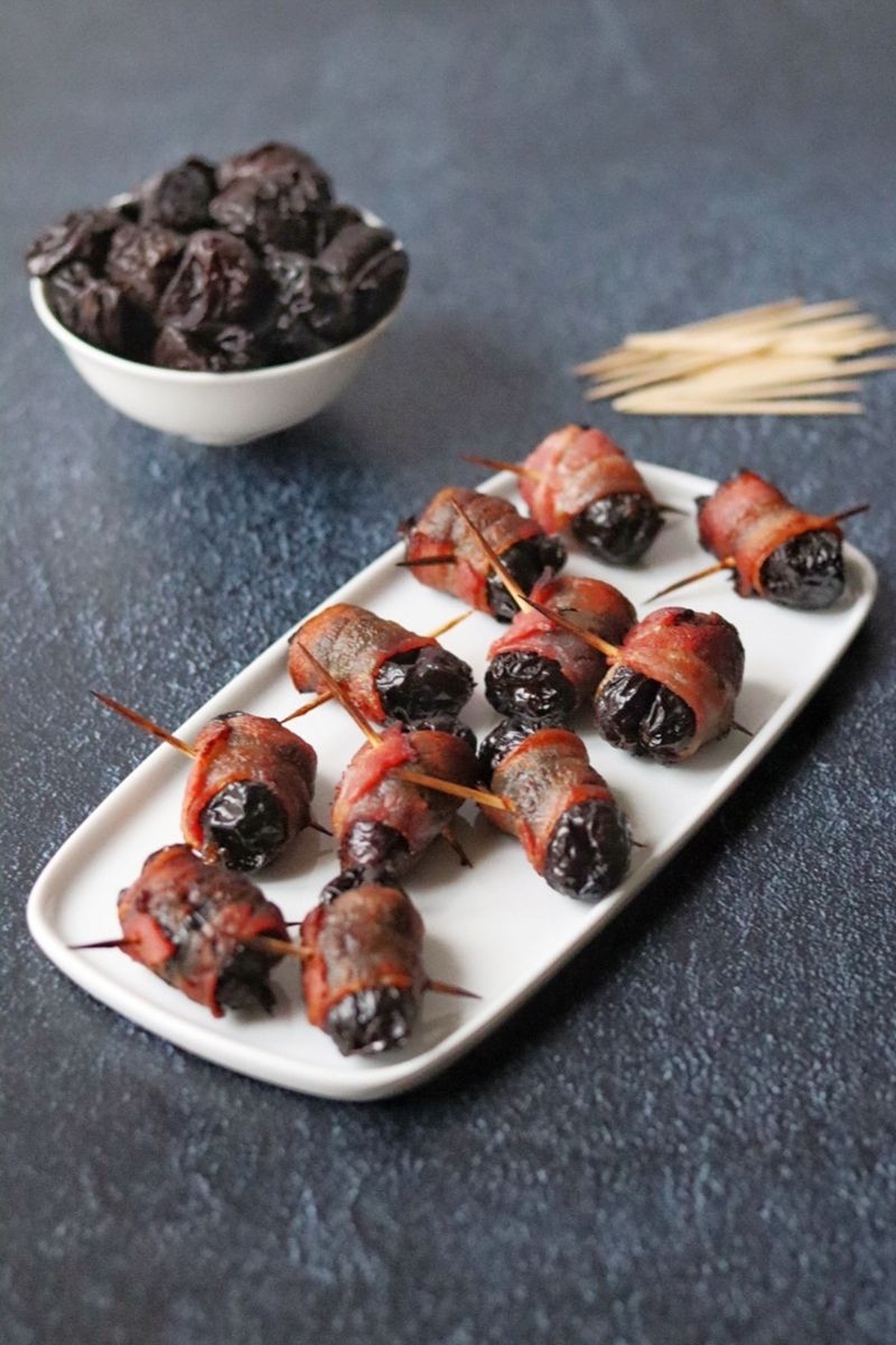 Prunes wrapped in bacon with a toothpick through the center.