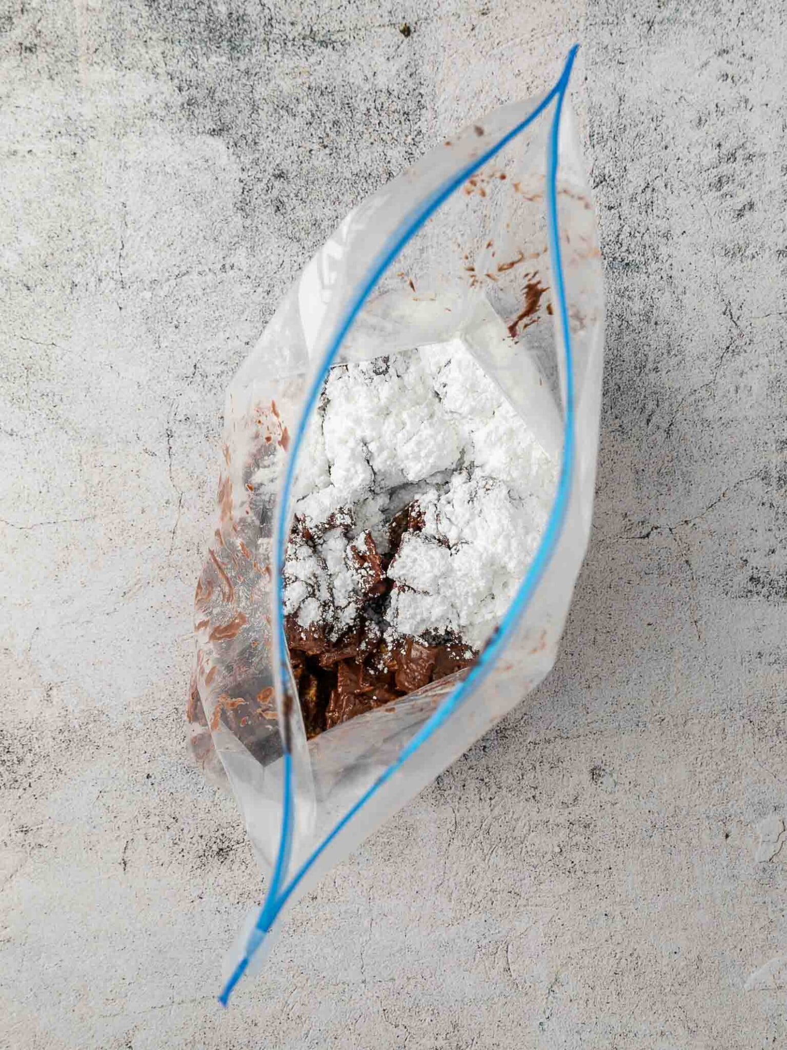 Chocolate coated cereal in plastic bag with powdered sugar on top.