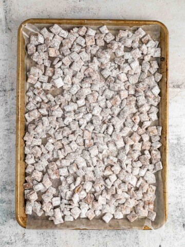 Powdered sugar coated cereal on baking sheet with wax paper lining.