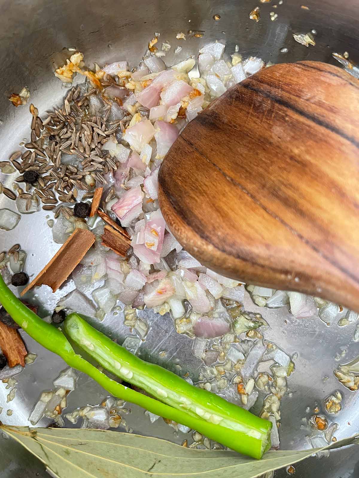 Garlic and whole spices in a large pot with oil.