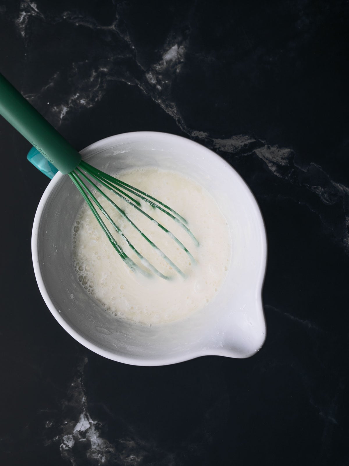 Whisking icing in the mixing bowl whit a whisk.