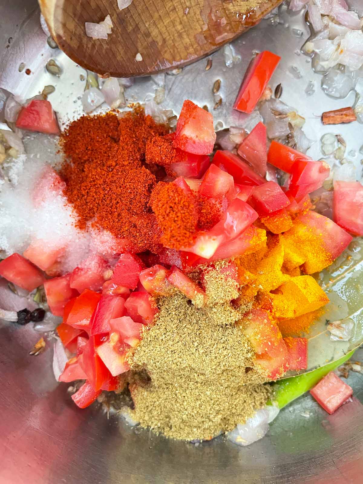 Tomatoes and ground spices are added to the pot.