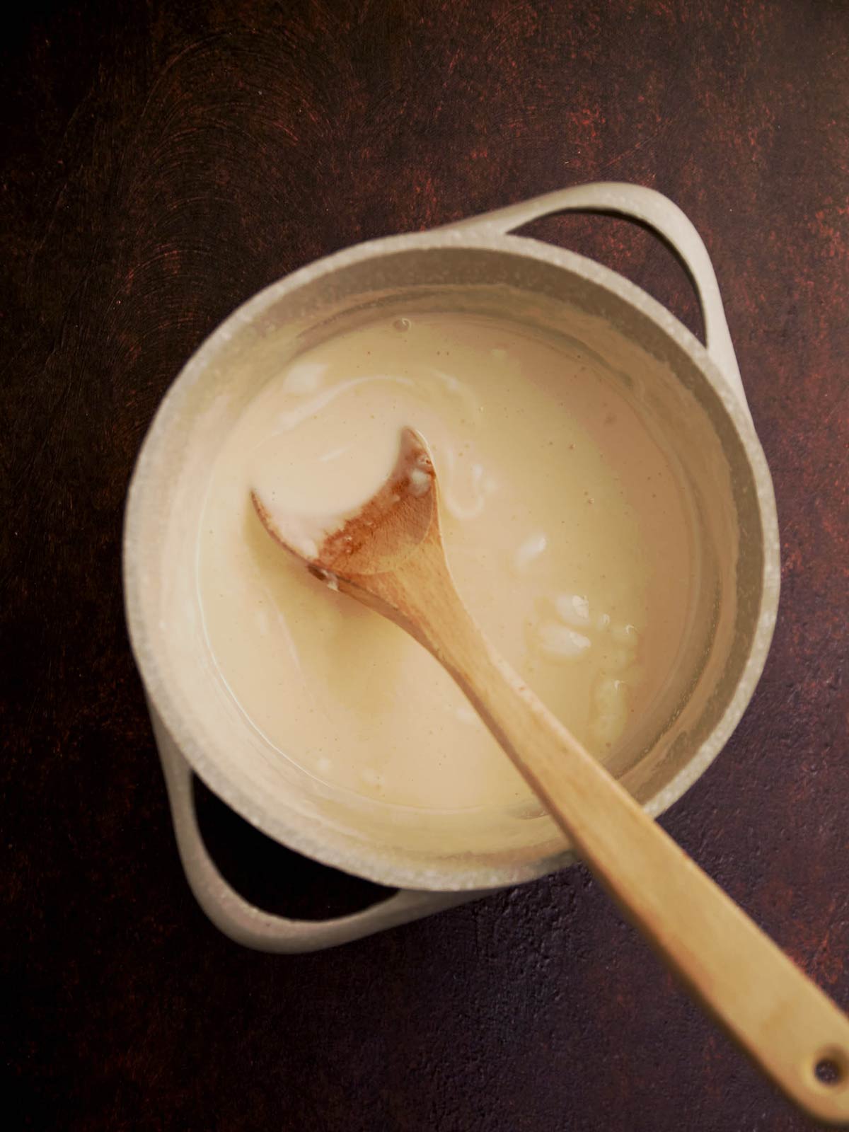 Melted fudge ingredients in the pot with wooden spoon.