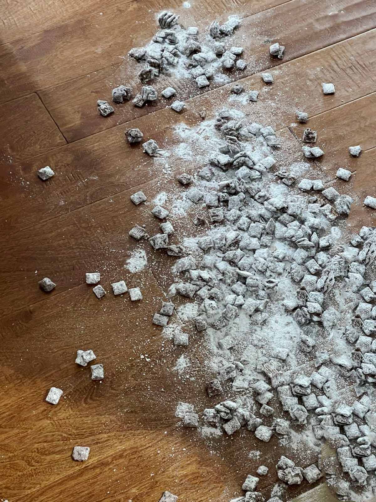 Bowl of powdered sugar-coated cereal spilled on hardwood flooring.
