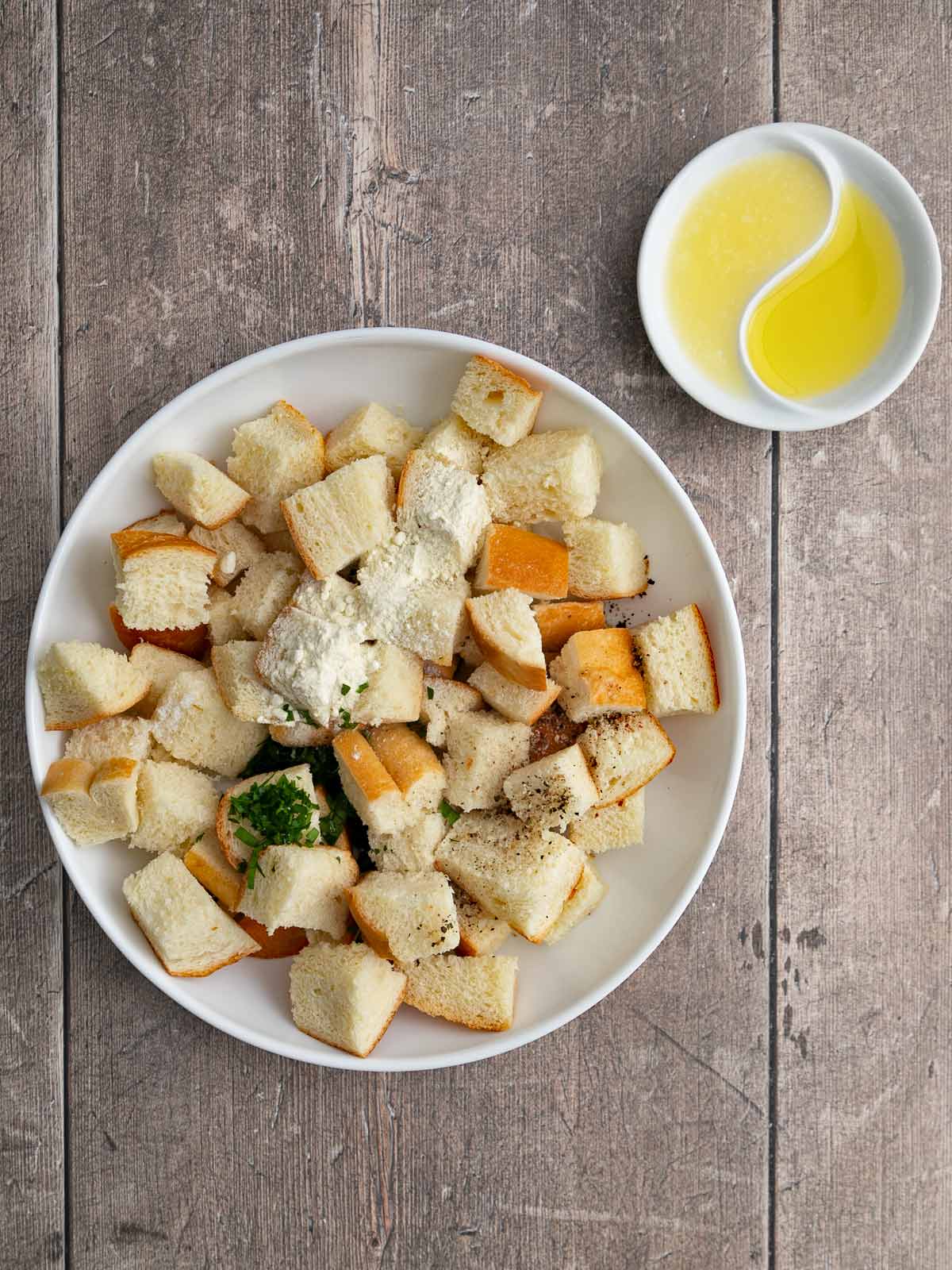 Bowl with bread cubes, cheese powder, pepper, salt, and parsley.